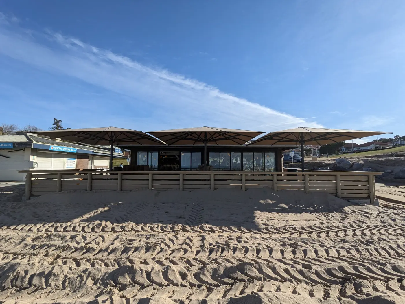 Parasols ouverts au-dessus d'un restaurant de plage, vus depuis le sable