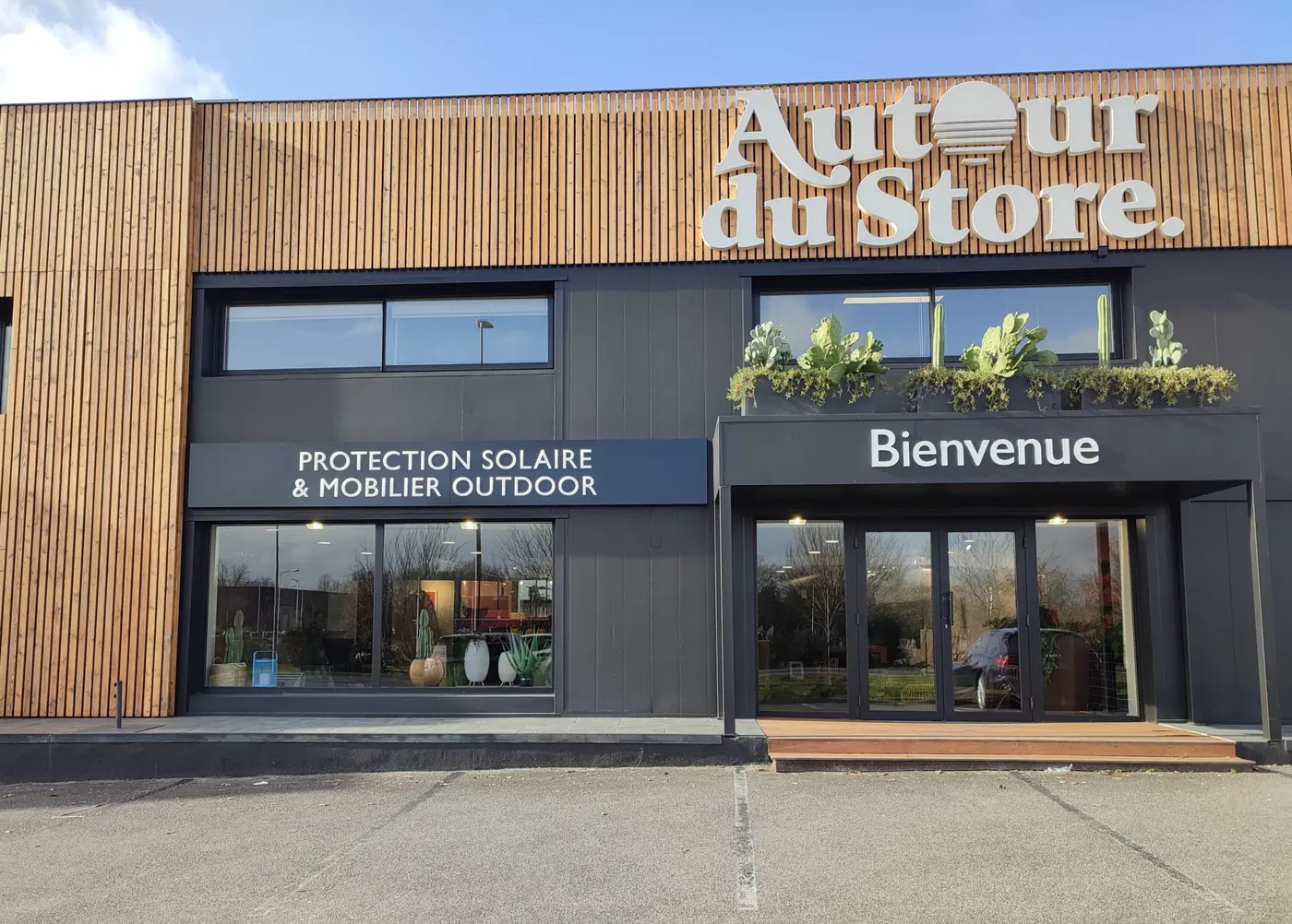 Façade du showroom Autour du Store à Bayonne : bardage bois, grande enseigne, vitrines « Protection solaire & mobilier outdoor » et « Bienvenue »