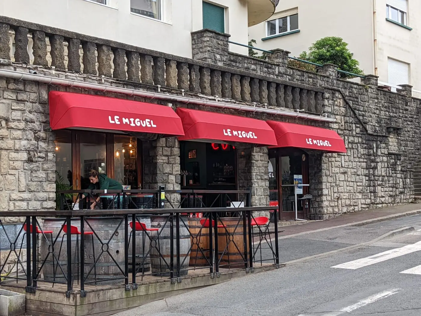 Stores rouges de Le Miguel, avec le nom imprimé en blanc sur chaque lambrequin