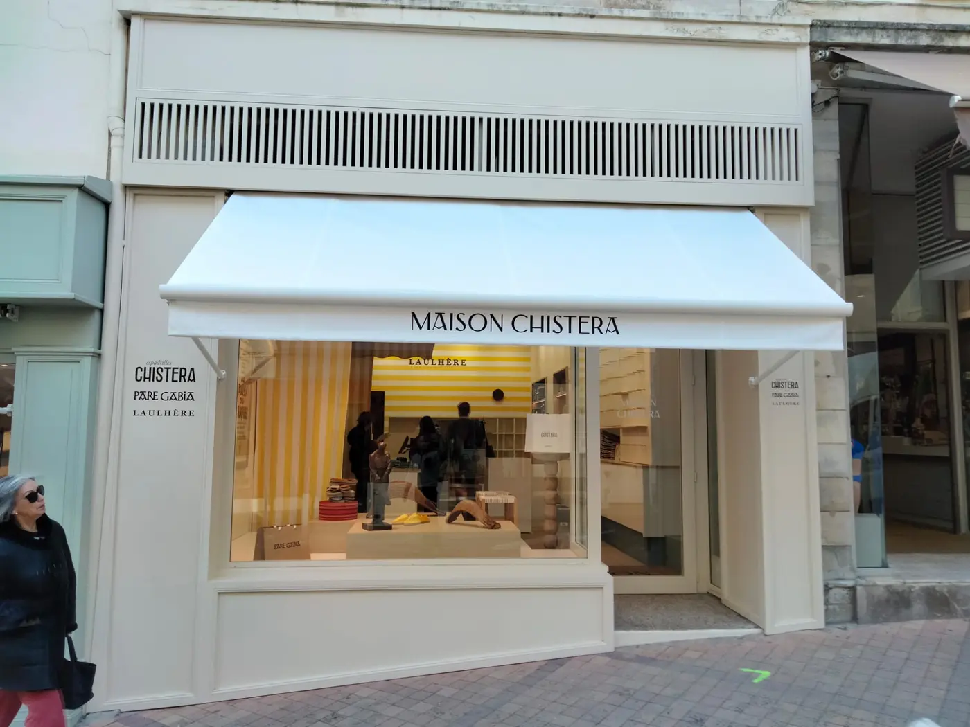 Store à projection blanc au nom de Maison Chistera au-dessus de la vitrine