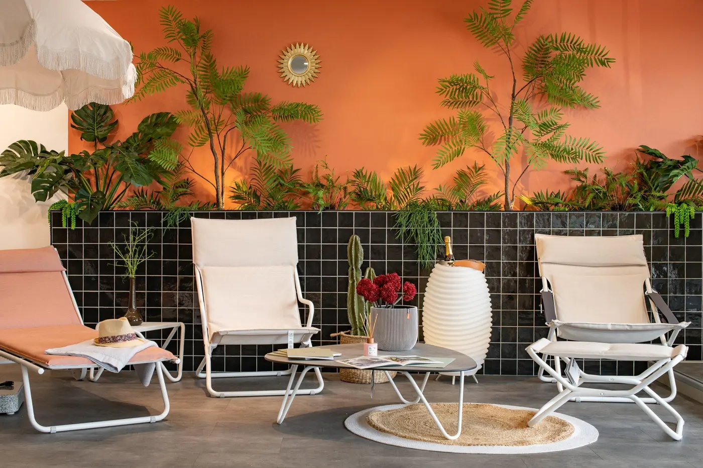 Fauteuils et chaises longues blancs devant un mur orange et des plantes