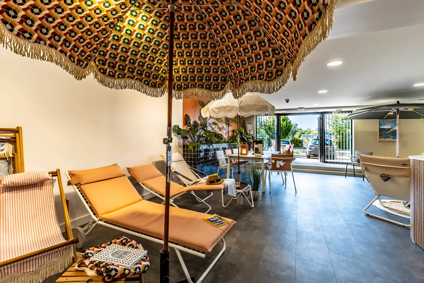 Showroom avec parasols à franges, chaises longues orange et tables d'extérieur