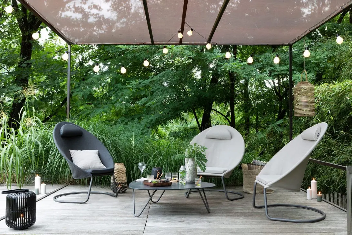 Fauteuils en corde sous une pergola toile éclairée par une guirlande