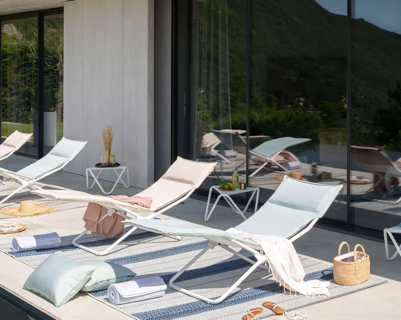 Chaises longues claires alignées au bord d'une terrasse