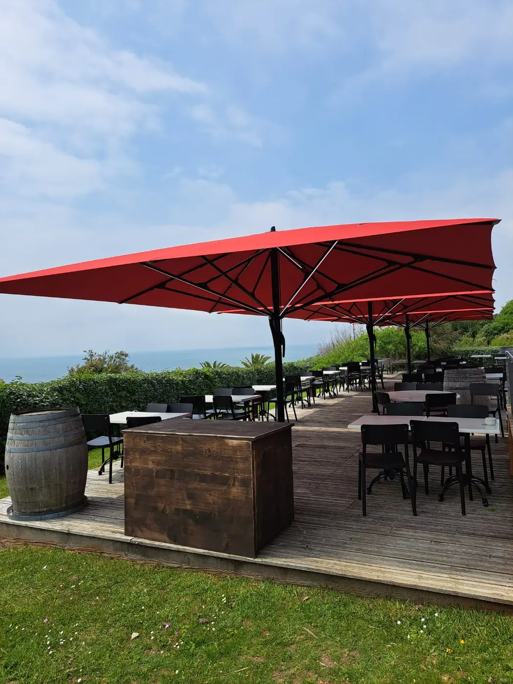 Grands parasols rouges au-dessus d'une terrasse de restaurant avec vue sur la mer