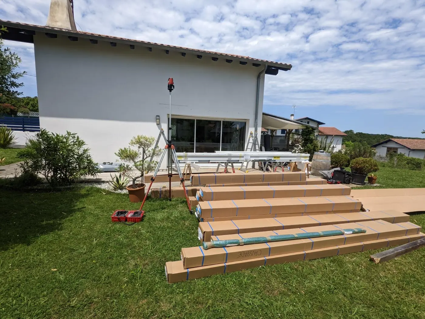 Pergola bioclimatique blanche posée contre une maison à Mouguerre, avec terrasse en bois