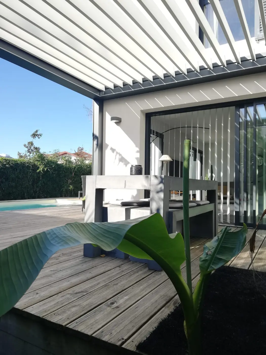 Pergola bioclimatique à lames au-dessus d'une terrasse, volets roulants sur la baie