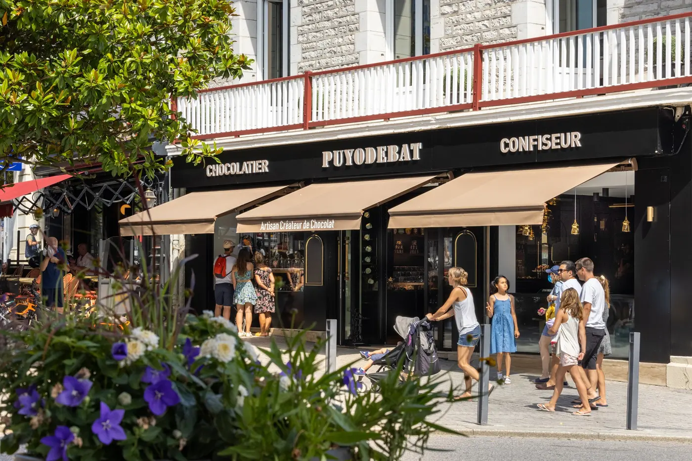 Stores bannes beiges au-dessus de la vitrine de Puyodebat à Biarritz, passants sur le trottoir