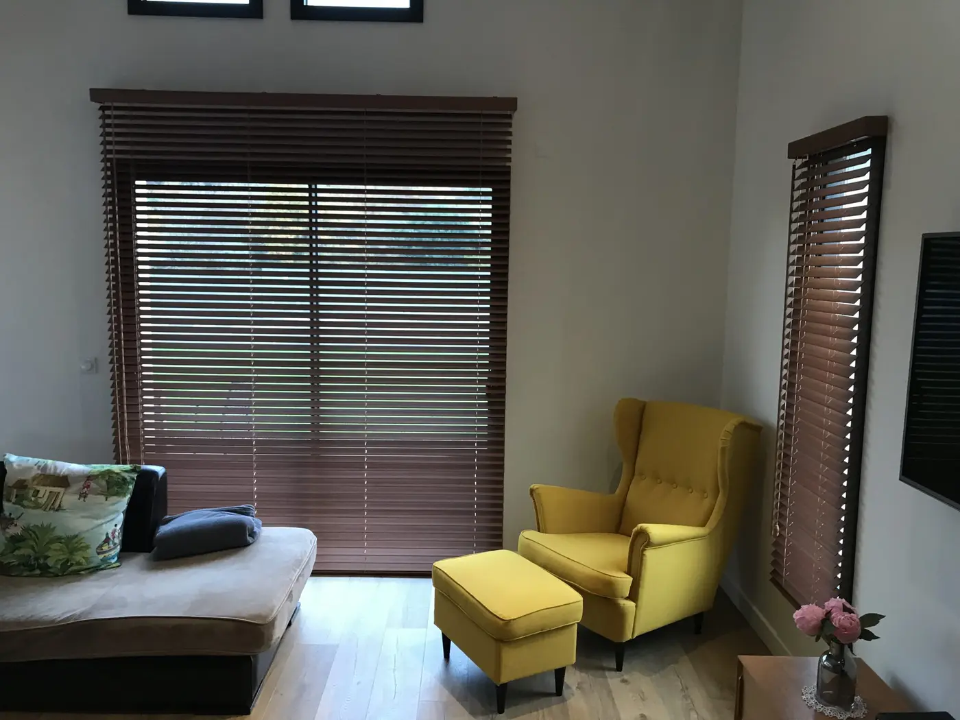 Stores vénitiens en bois foncé dans un salon avec fauteuil jaune