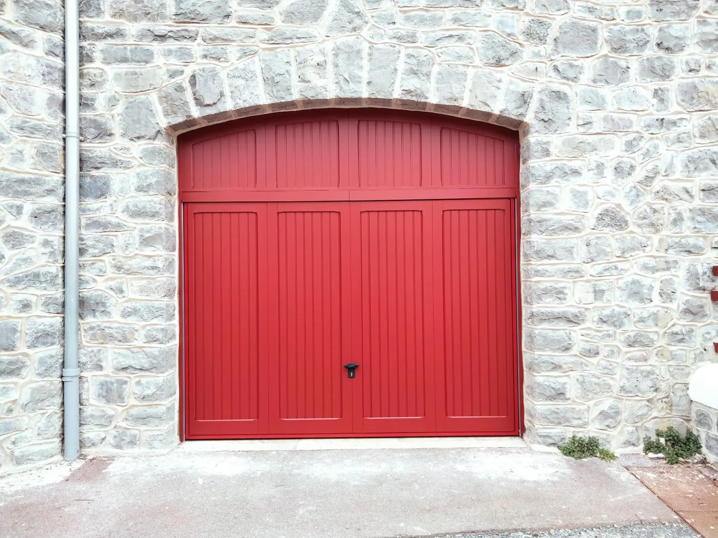 Porte de garage rouge avec habillage bois sur mesure dans un mur de pierre, Villa Casablanca