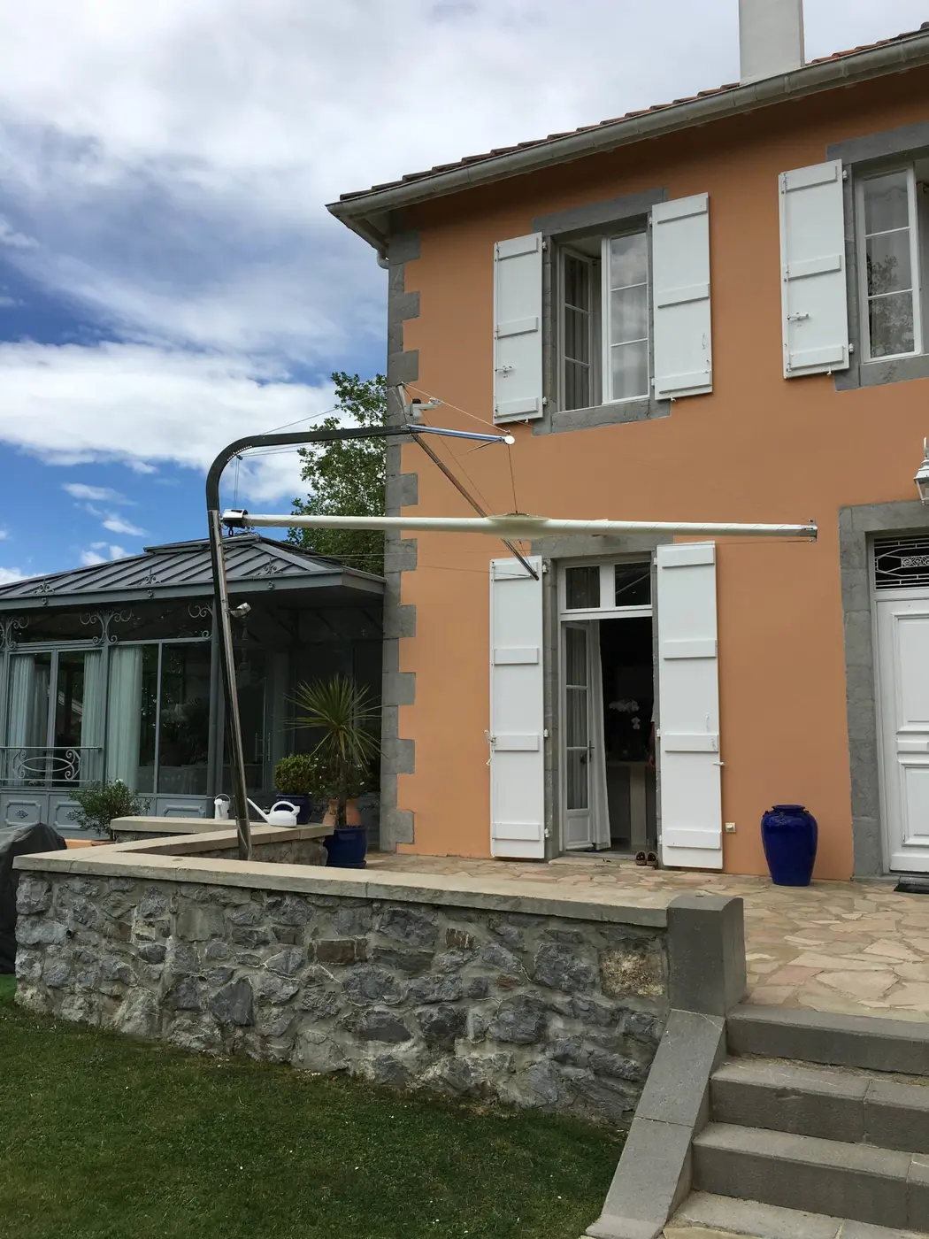 Voile d'ombrage blanche tendue au-dessus d'une terrasse devant une maison orange