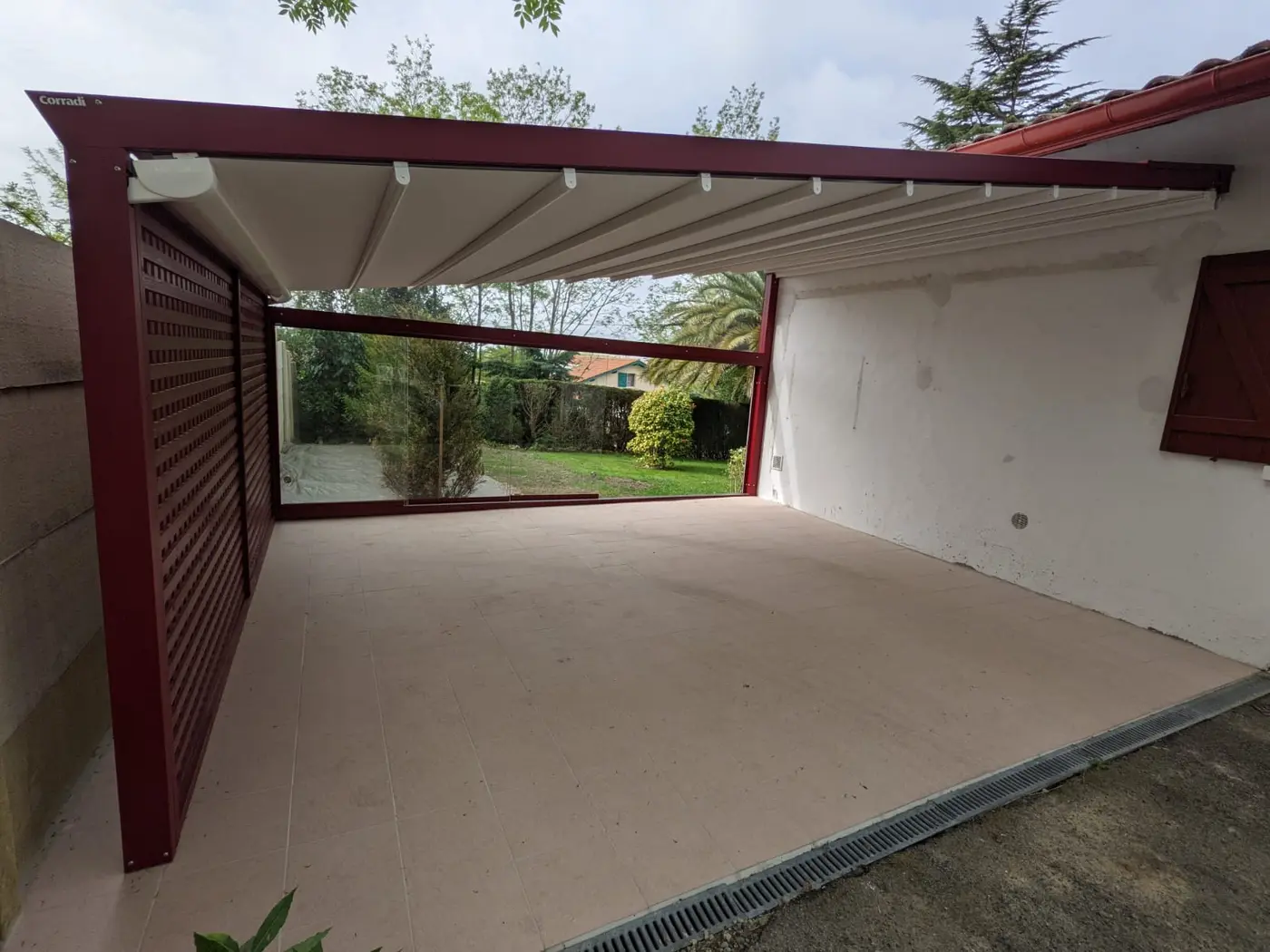 Pergola bordeaux à toit en toile, avec un panneau ajouré sur le côté